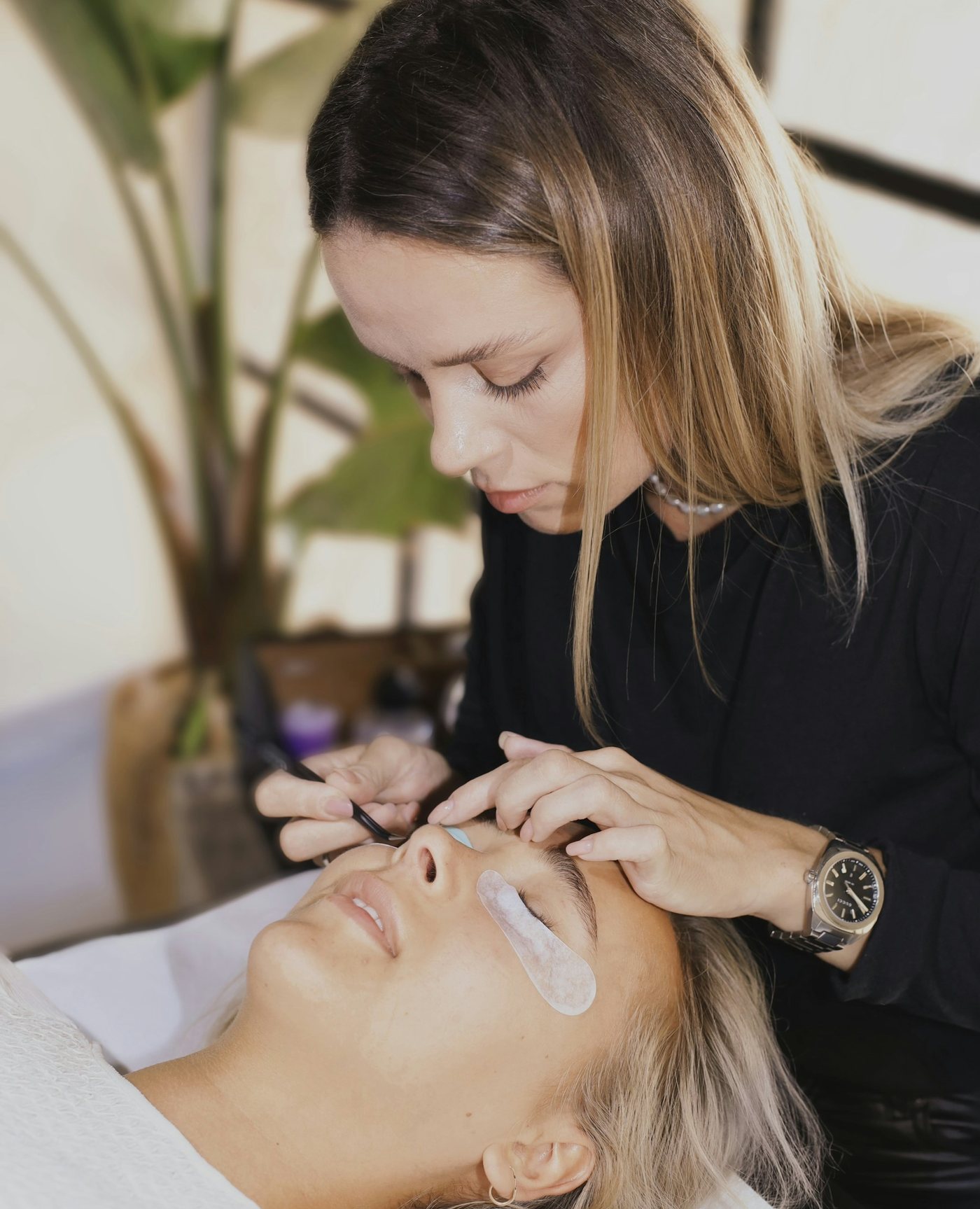 A lash artist applying lash extensions to a client in a bright studio